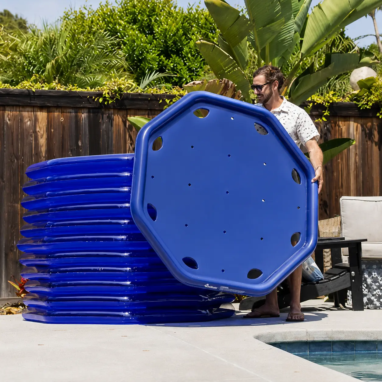 Person holding a floating solar pool heater panel at the poolside